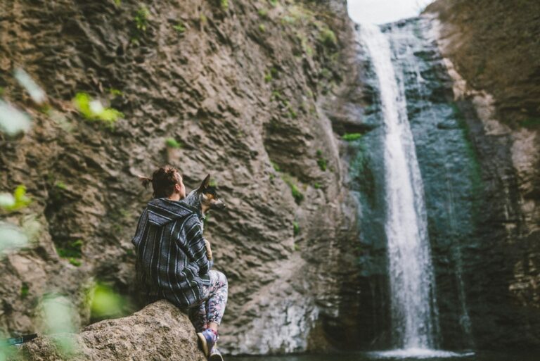 Person sitting next to waterfall.