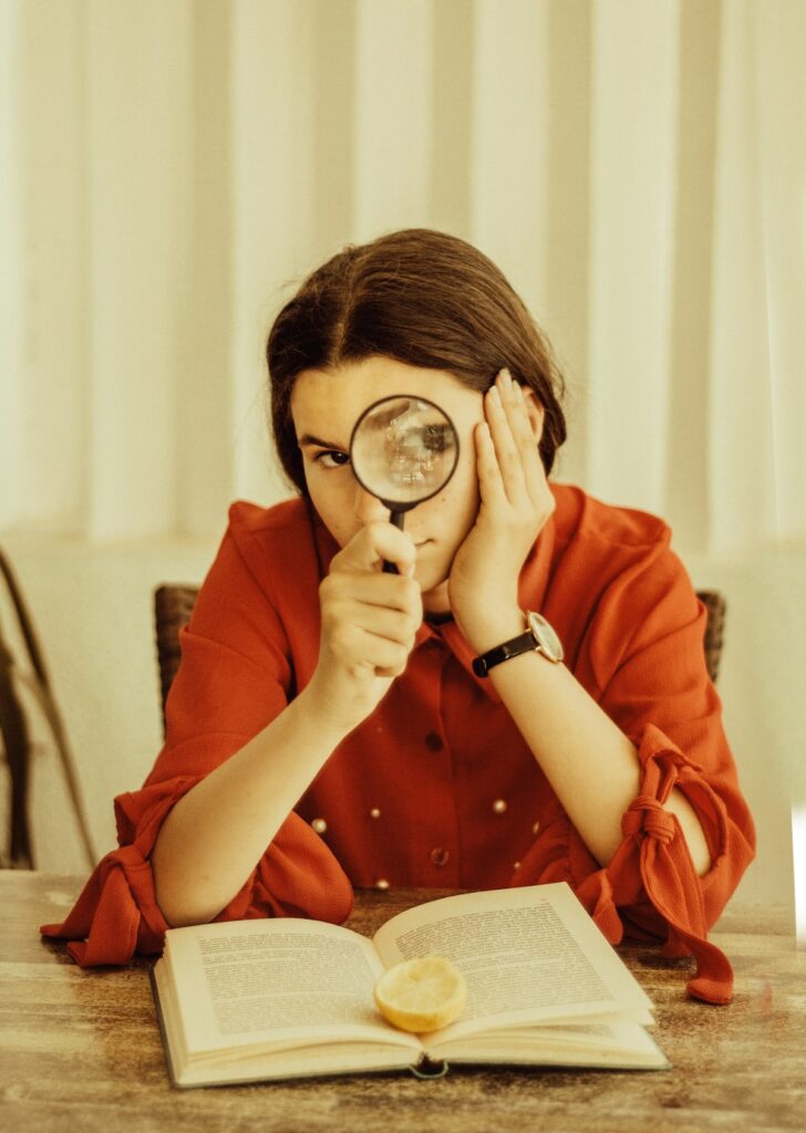 Woman holds magnifying glass.