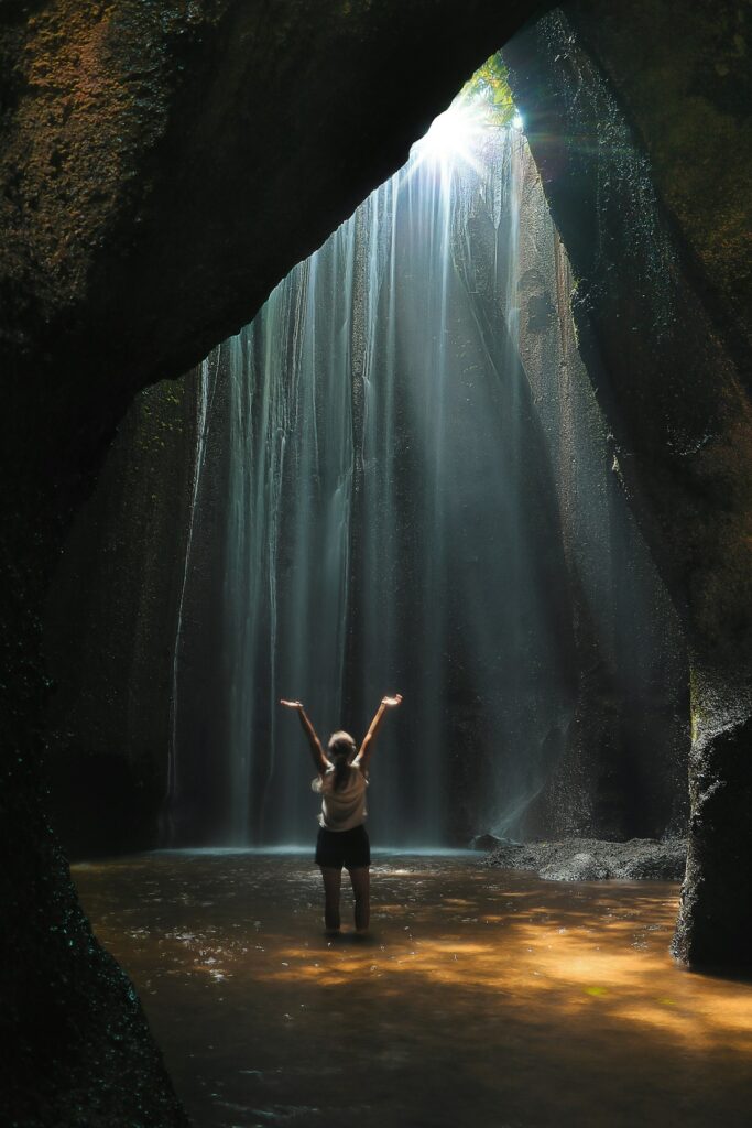 Peson in cave under waterfall.